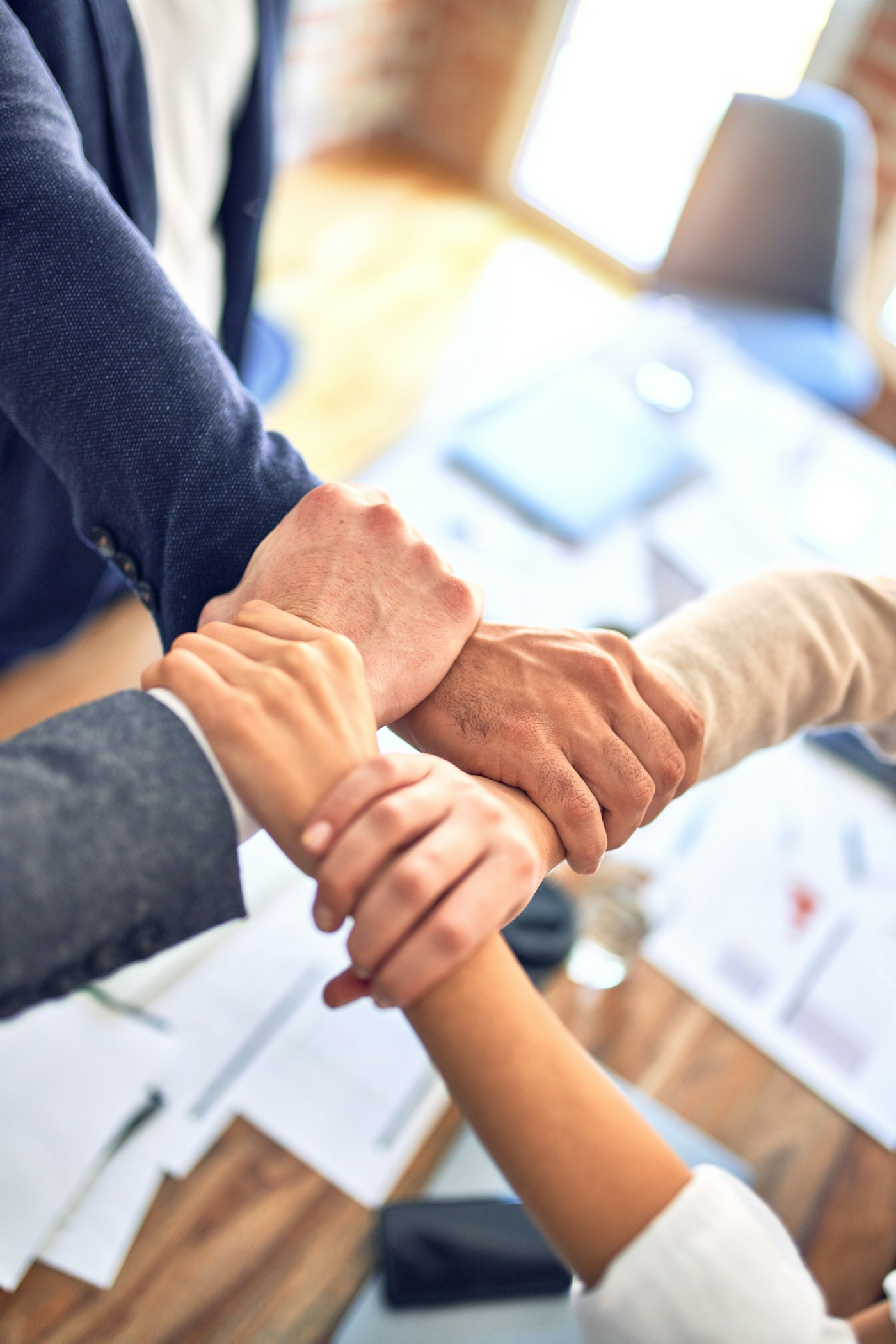 Manos unidas de un equipo de trabajo sobre la mesa de reuniones